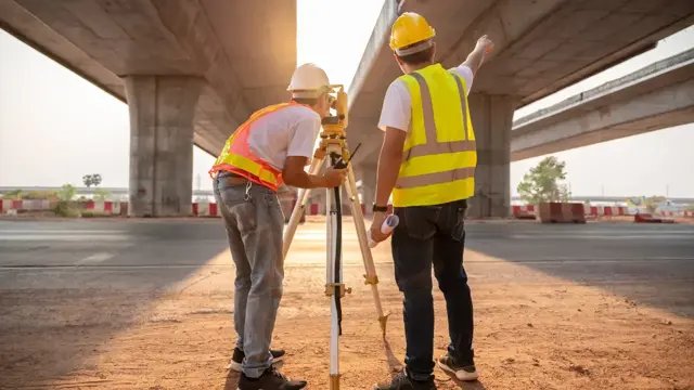 Survey engineers using a total station under a bridge structure